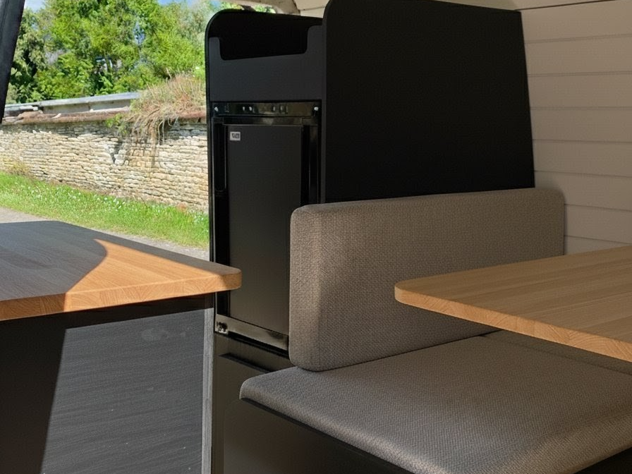 Aménagement intérieur de van moderne et minimaliste avec bois clair et mobilier noir mat.