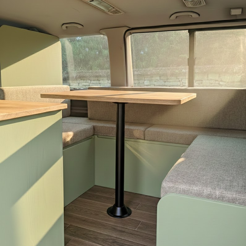Aménagement intérieur de van moderne : banquette en U vert sauge et table en bois.